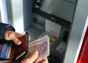 person holding brown leather wallet and banknotes