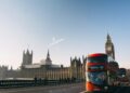 red double-decker bus passing Palace of Westminster, London during daytime