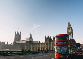 red double-decker bus passing Palace of Westminster, London during daytime