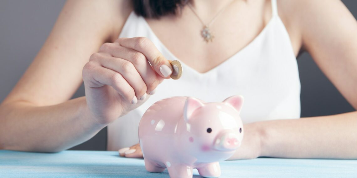 woman in white tank top holding pink pig figurine