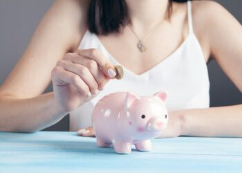woman in white tank top holding pink pig figurine
